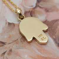 Gold pendant necklace with '14K' marking on a floral background