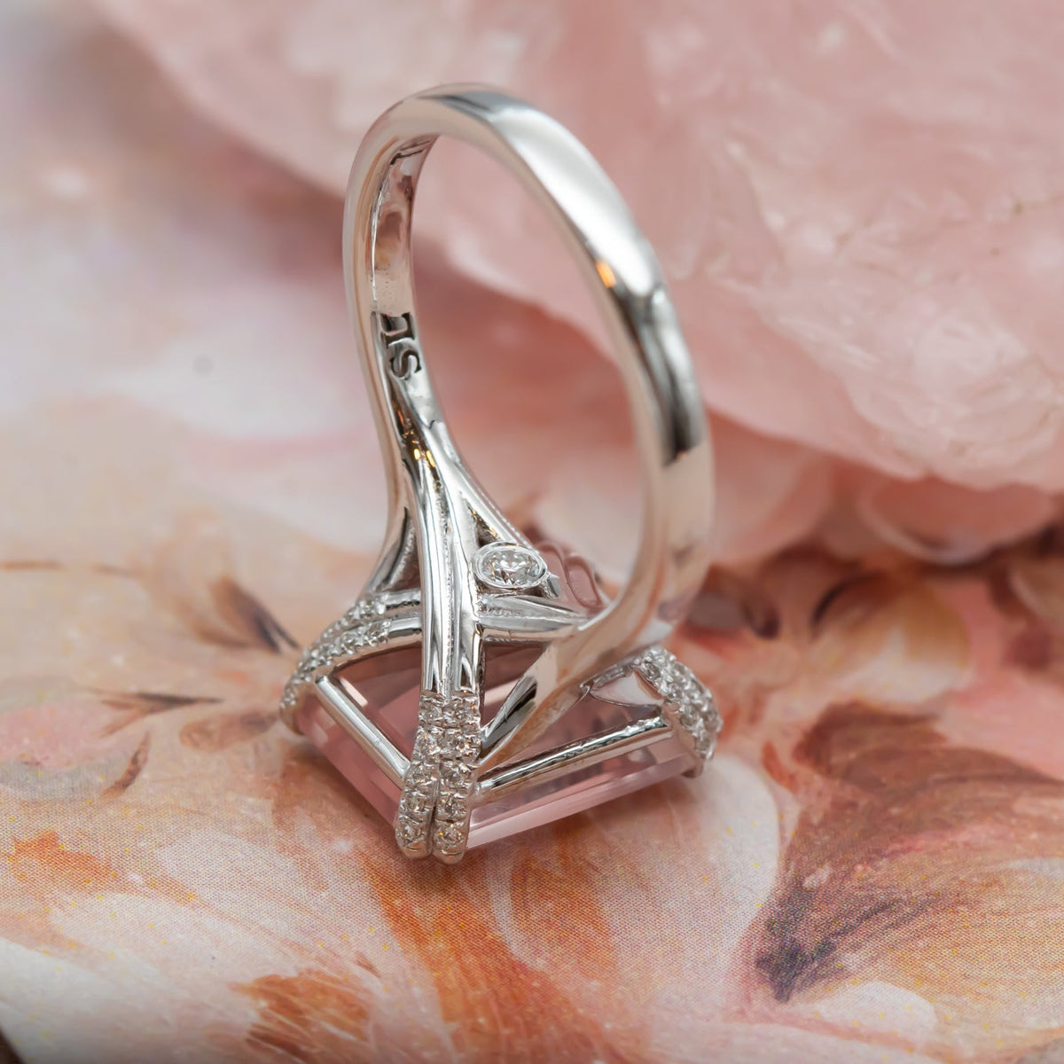 Macro of a 14K rose gold rose quartz ring with diamond-set prongs and crossover gallery