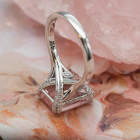 Macro of a 14K rose gold rose quartz ring with diamond-set prongs and crossover gallery