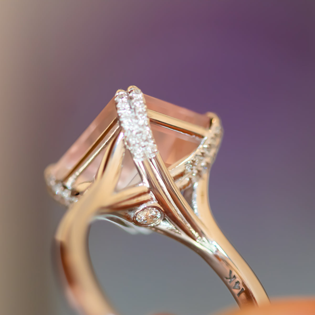 Macro of a 14K rose gold rose quartz ring with diamond-set prongs and crossover gallery and hidden diamond