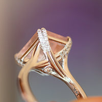 Macro of a 14K rose gold rose quartz ring with diamond-set prongs and crossover gallery and hidden diamond
