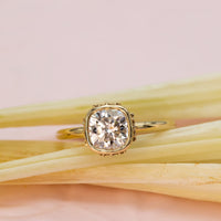 Elegant cushion-cut diamond ring in solid gold with sculpted bezel and side diamonds, handcrafted in a vintage-inspired modern design.

