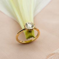 Elegant cushion-cut diamond ring in solid gold with sculpted bezel and side diamonds, handcrafted in a vintage-inspired modern design.
