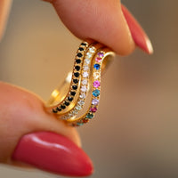 Stack of three gold wave rings – rainbow sapphire ring, black diamond ring, and white diamond ring – handcrafted stacking set by Sivan Lotan Jewelry