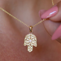 Gold Hamsa pendant necklace with a diamond on neck