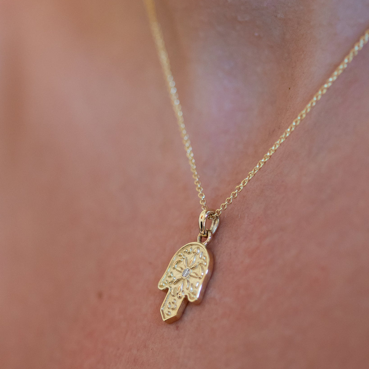 Gold Hamsa pendant necklace with a diamond on body