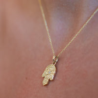Gold Hamsa pendant necklace with a diamond on body