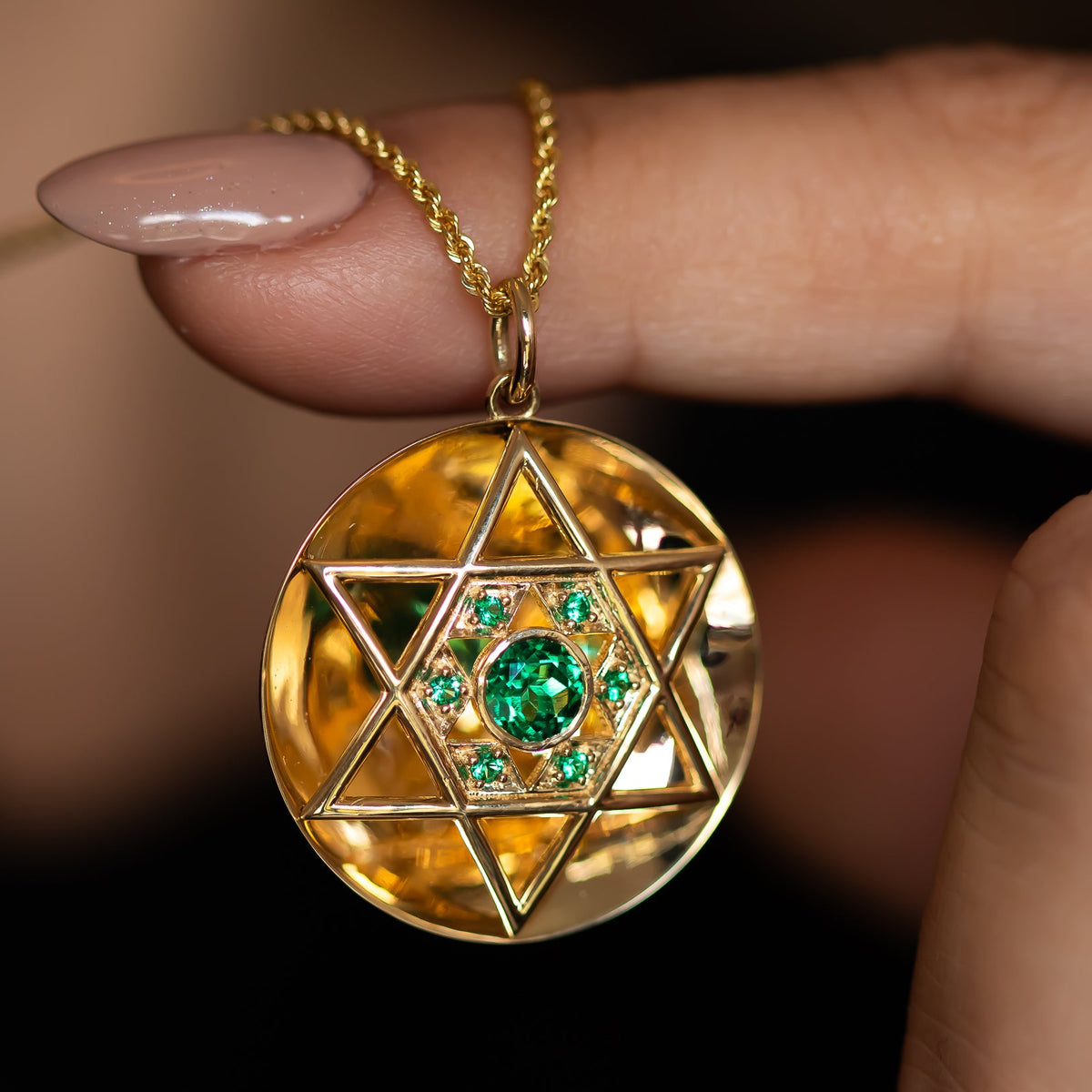 Close-up of gold Star of David pendant with emeralds on chain