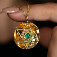 Close-up of gold Star of David pendant with emeralds on chain
