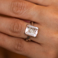 Rose quartz cocktail ring worn on hand, emerald-cut pink stone in a polished gold setting
