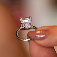 Rose quartz ring held up to show the split-shoulder band and diamond-lined crossover gallery