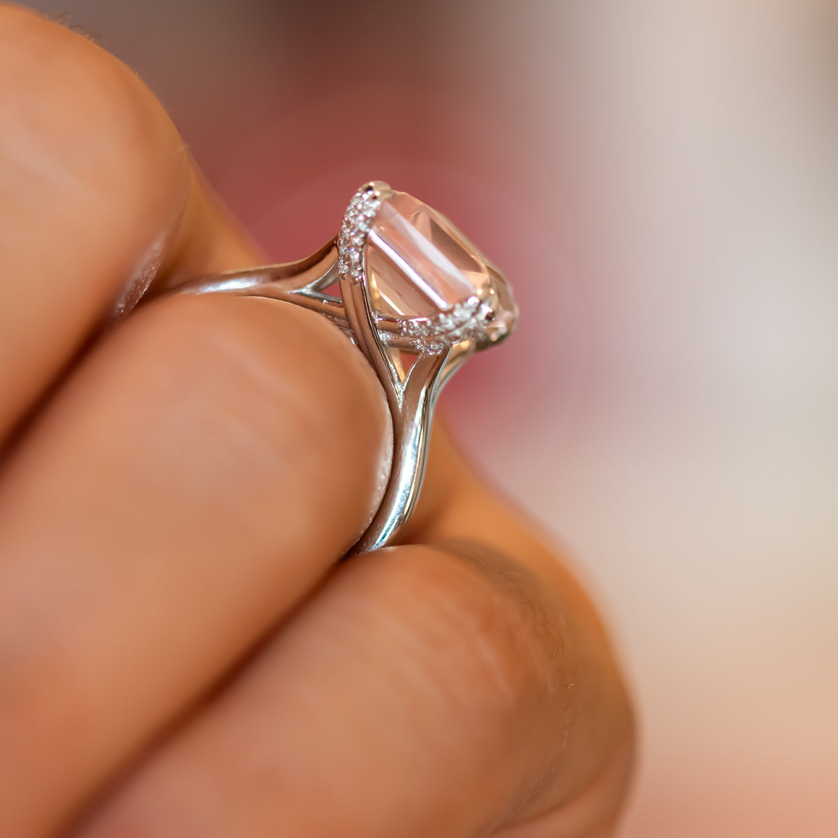 Side view of rose quartz ring with diamond-lined gallery raised on a tapered gold band