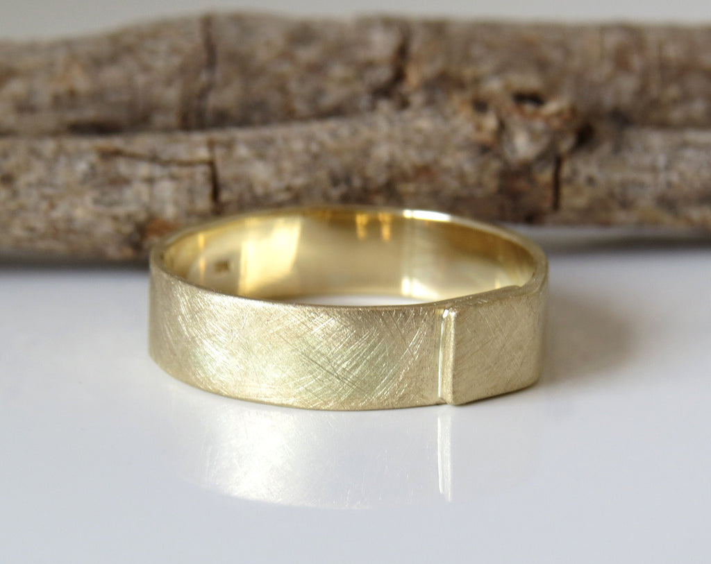 A brushed gold men's wedding band with a textured design, displayed on a white background.