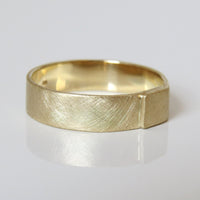 A brushed gold men's wedding band with a textured design, displayed on a white background.