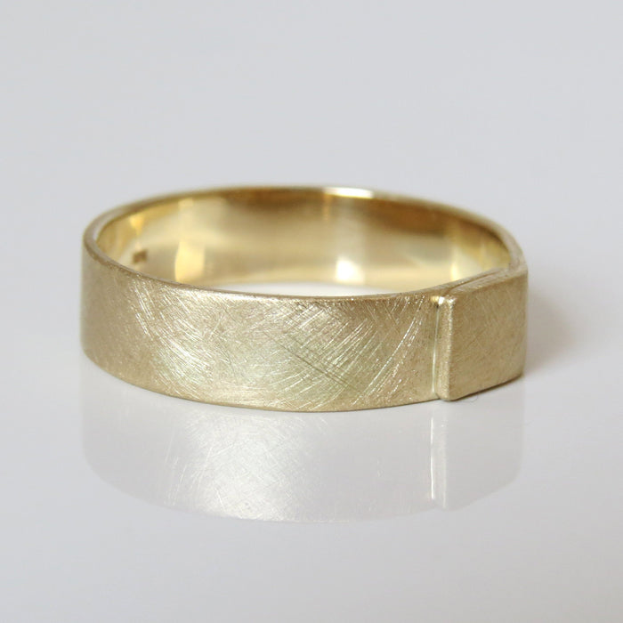A brushed gold men's wedding band with a textured design, displayed on a white background.